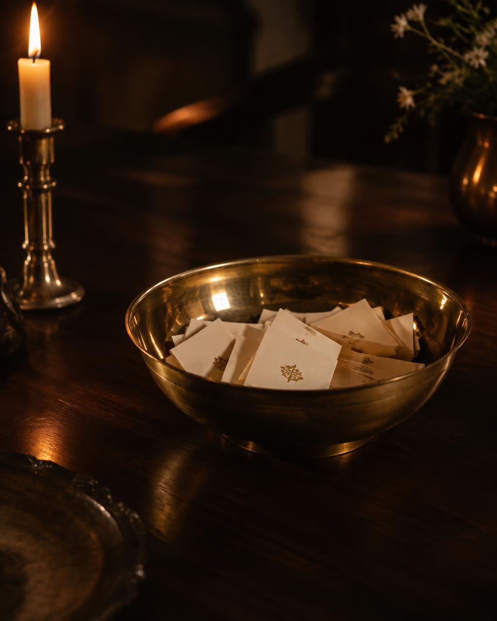 Polished brass bowl filled with folded name cards on a dark wooden table